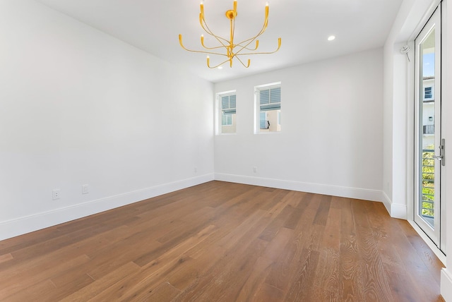 unfurnished room with hardwood / wood-style flooring and an inviting chandelier