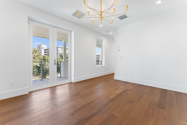 empty room featuring wood-type flooring, an inviting chandelier, and french doors