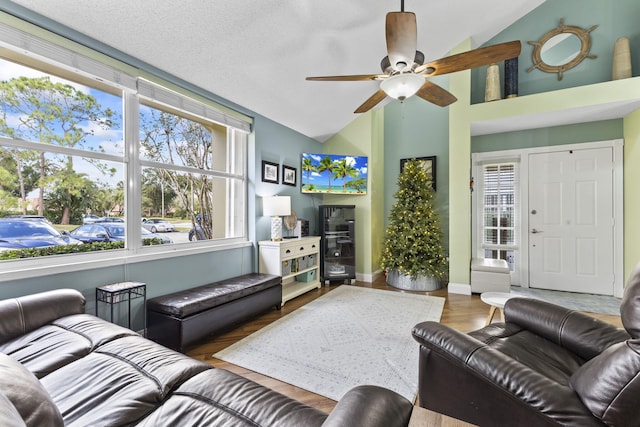 living room with a textured ceiling, ceiling fan, wood-type flooring, and vaulted ceiling