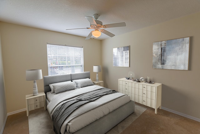 bedroom with ceiling fan, light carpet, and a textured ceiling