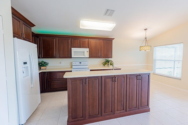 kitchen featuring sink, white appliances, light tile patterned floors, a kitchen island with sink, and decorative light fixtures