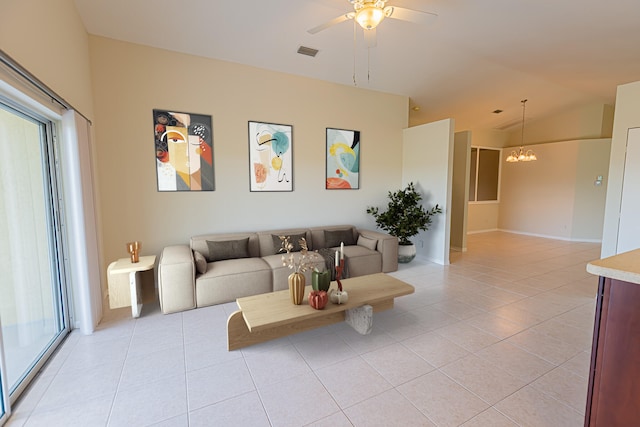 living room featuring ceiling fan with notable chandelier, vaulted ceiling, and light tile patterned floors