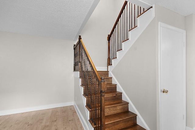 stairs with hardwood / wood-style floors and a textured ceiling