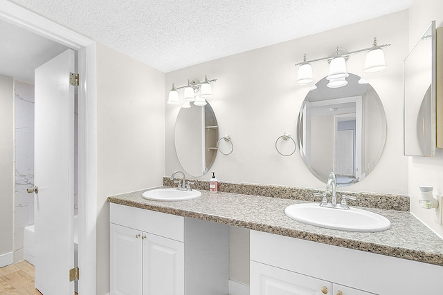 bathroom with hardwood / wood-style floors, vanity, shower / bath combination, and a textured ceiling