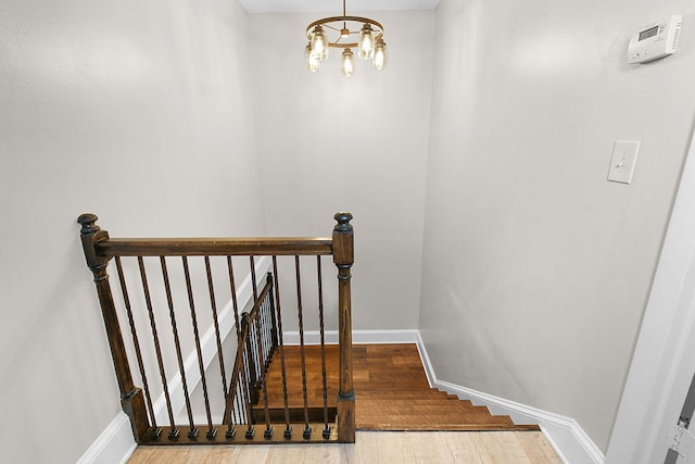 staircase with hardwood / wood-style floors and an inviting chandelier