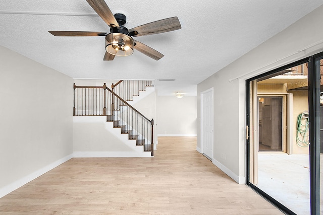 stairs featuring ceiling fan, wood-type flooring, and a textured ceiling