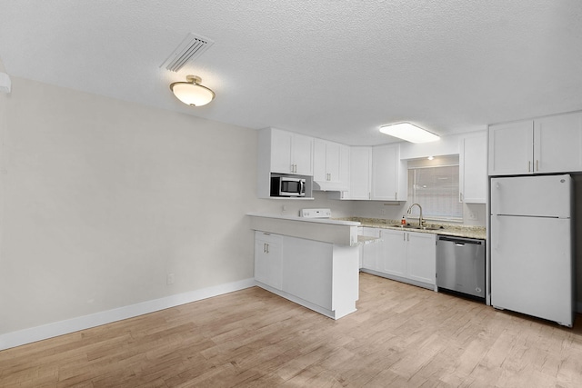 kitchen with sink, light hardwood / wood-style flooring, white cabinetry, kitchen peninsula, and stainless steel appliances