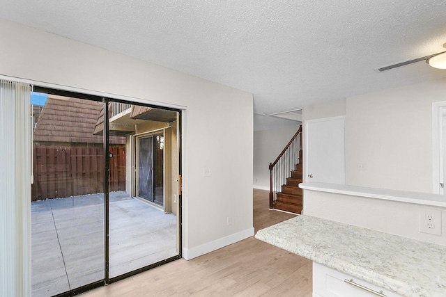 unfurnished room with ceiling fan, light hardwood / wood-style flooring, and a textured ceiling