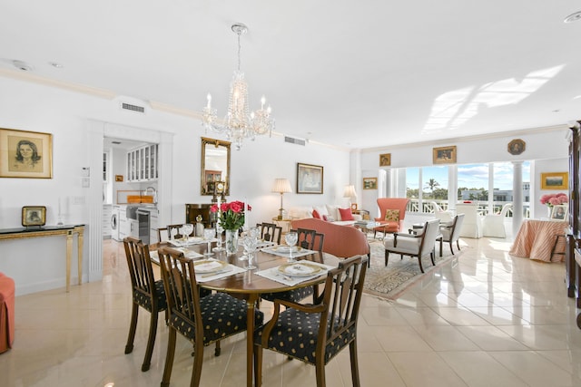 dining space with crown molding, sink, light tile patterned floors, an inviting chandelier, and independent washer and dryer