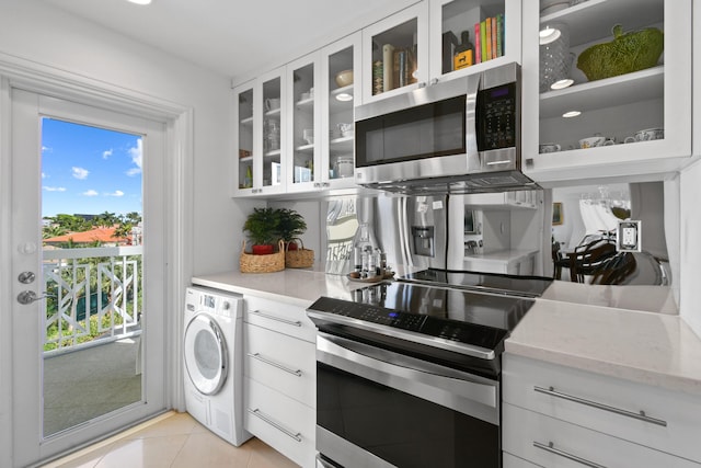 kitchen featuring a wealth of natural light, washer / clothes dryer, white cabinetry, and stainless steel appliances