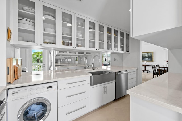 kitchen featuring white cabinets, sink, dishwasher, washer / dryer, and light tile patterned flooring