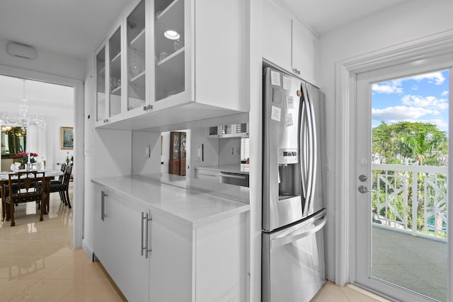 kitchen with a chandelier, appliances with stainless steel finishes, white cabinetry, and light tile patterned flooring