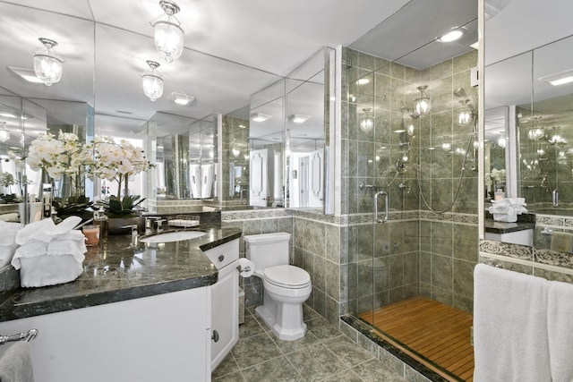 bathroom with walk in shower, tile patterned flooring, toilet, vanity, and tile walls