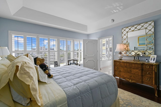 bedroom with a tray ceiling and wood-type flooring