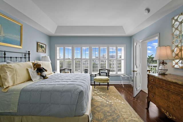 bedroom with a raised ceiling and dark wood-type flooring