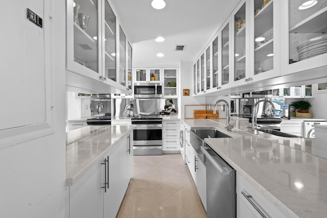 kitchen with light stone countertops, white cabinetry, sink, and appliances with stainless steel finishes