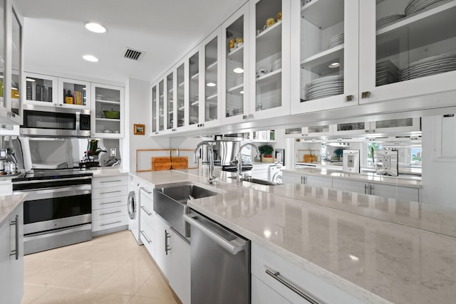 kitchen with light stone countertops, white cabinetry, sink, and appliances with stainless steel finishes