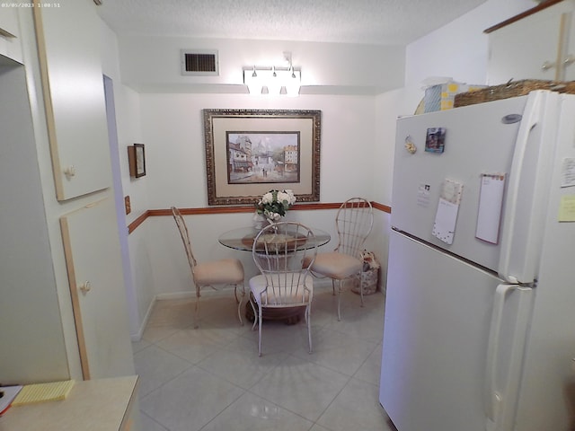 dining space featuring light tile patterned flooring and a textured ceiling