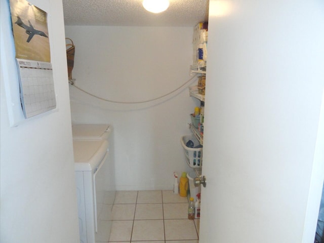 bathroom featuring washing machine and clothes dryer, tile patterned flooring, and a textured ceiling