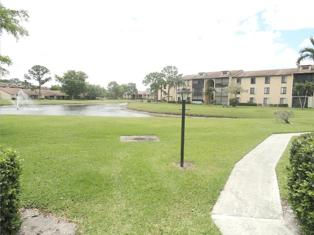 surrounding community with a water view and a yard