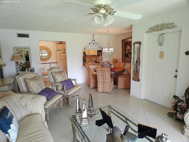 living room featuring ceiling fan with notable chandelier, light tile patterned floors, and a textured ceiling