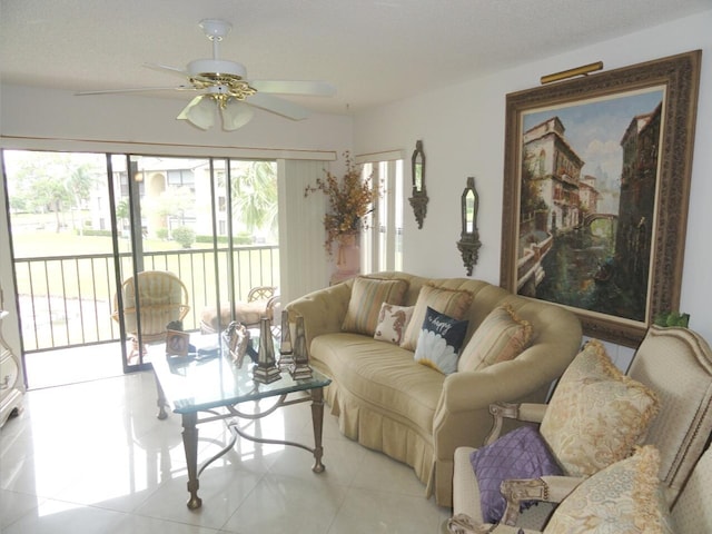 living room with ceiling fan, light tile patterned flooring, and a textured ceiling