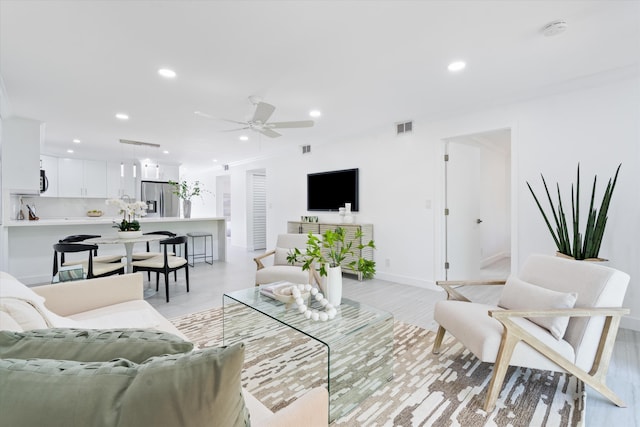 living room with light hardwood / wood-style flooring and ceiling fan