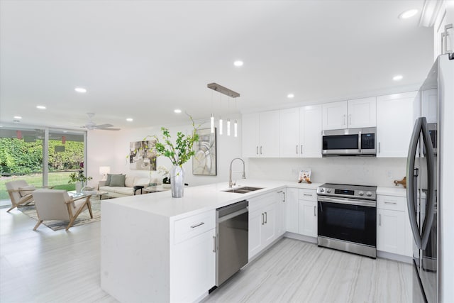 kitchen with white cabinetry, sink, hanging light fixtures, kitchen peninsula, and appliances with stainless steel finishes