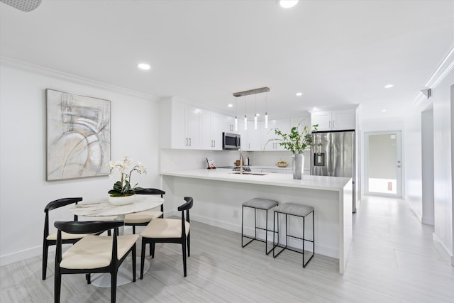 kitchen featuring pendant lighting, a breakfast bar, white cabinets, appliances with stainless steel finishes, and kitchen peninsula