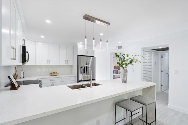 kitchen featuring stainless steel fridge, kitchen peninsula, sink, and hanging light fixtures