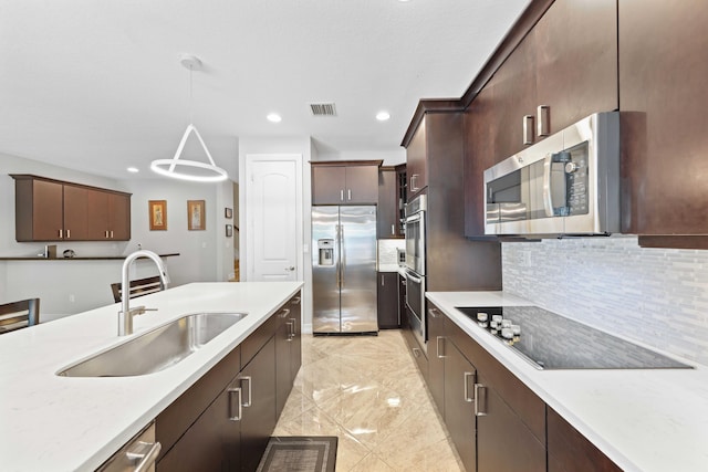 kitchen with decorative backsplash, dark brown cabinetry, stainless steel appliances, sink, and decorative light fixtures