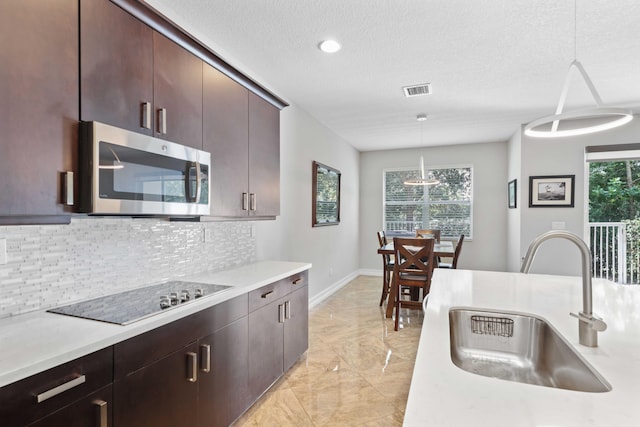 kitchen with black electric cooktop, hanging light fixtures, a healthy amount of sunlight, and sink