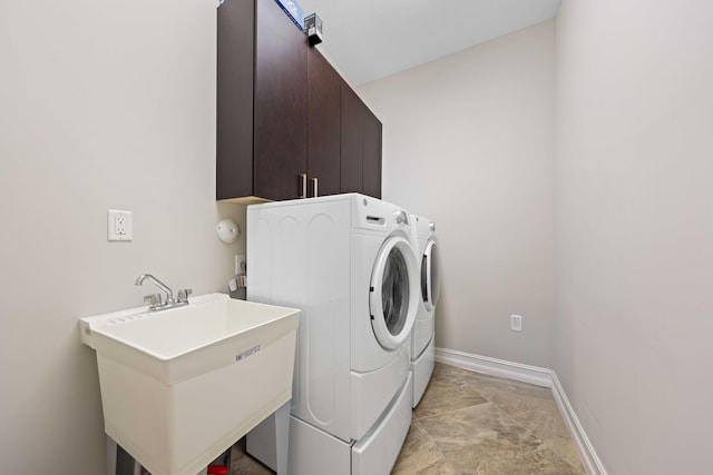 washroom featuring washing machine and clothes dryer, sink, and cabinets