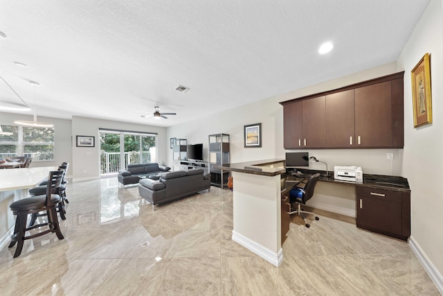 office area featuring a textured ceiling, ceiling fan, and built in desk