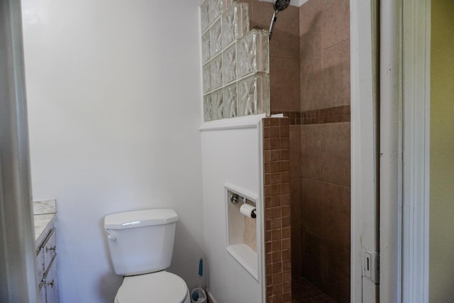 bathroom featuring tiled shower, vanity, and toilet