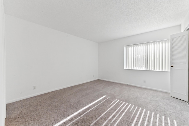 unfurnished room with light colored carpet and a textured ceiling