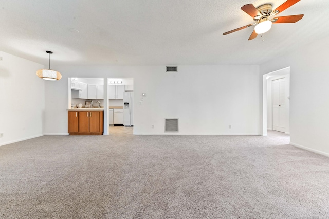 unfurnished living room featuring ceiling fan, light carpet, and a textured ceiling