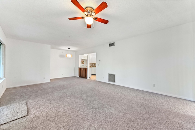 unfurnished living room featuring carpet, a textured ceiling, and ceiling fan