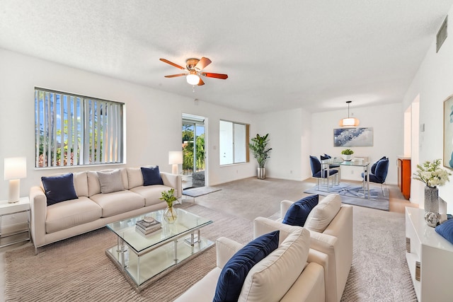 living room featuring light carpet, ceiling fan, and a textured ceiling