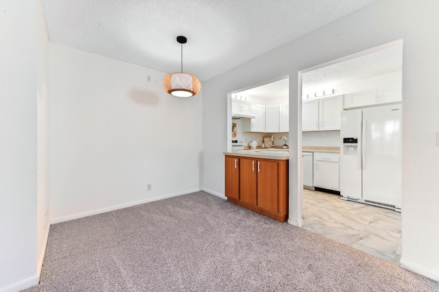 kitchen featuring decorative light fixtures, white cabinets, white refrigerator with ice dispenser, light carpet, and a textured ceiling