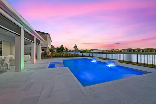 pool at dusk with pool water feature and a patio area