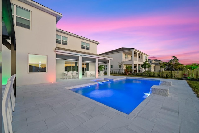 pool at dusk with a jacuzzi and a patio area