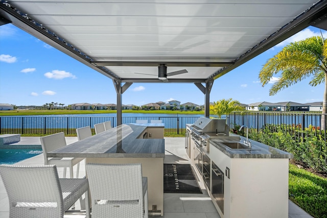 view of patio with sink, a water view, area for grilling, ceiling fan, and a grill