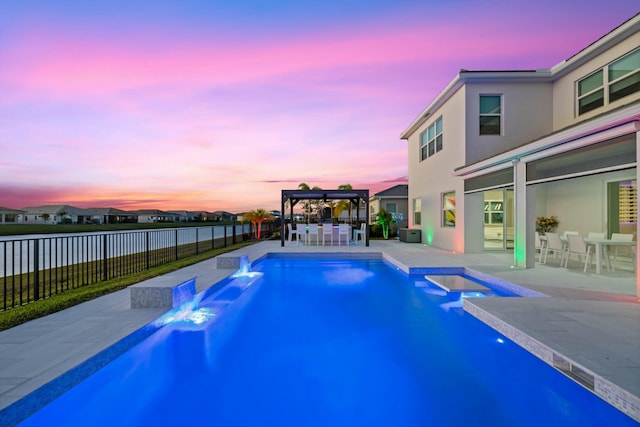 pool at dusk featuring an in ground hot tub, pool water feature, a patio, and a gazebo