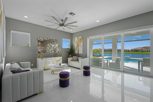 tiled living room featuring a water view and ceiling fan