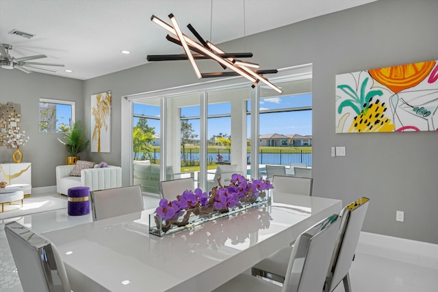 dining space with a water view and ceiling fan