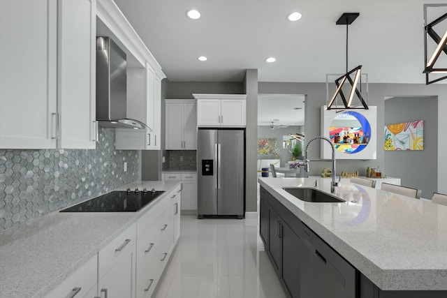 kitchen featuring wall chimney exhaust hood, sink, white cabinetry, an island with sink, and black appliances