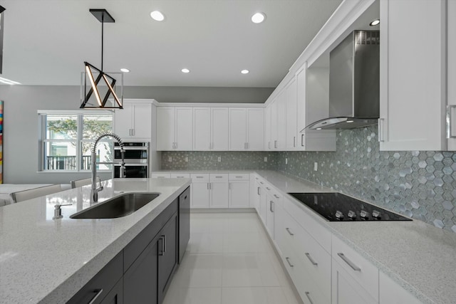 kitchen with white cabinetry, hanging light fixtures, stainless steel appliances, and wall chimney exhaust hood