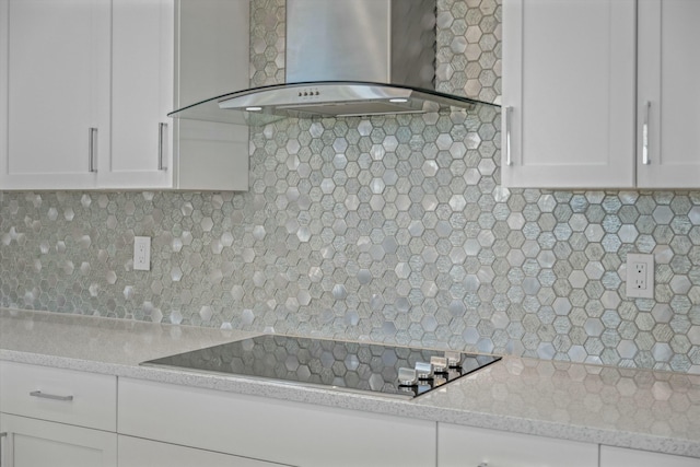 kitchen featuring white cabinetry, backsplash, black electric stovetop, light stone countertops, and wall chimney exhaust hood