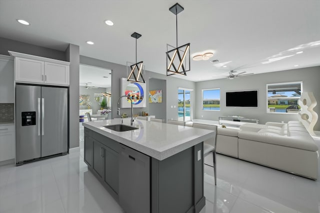 kitchen with pendant lighting, dishwasher, sink, white cabinets, and stainless steel fridge